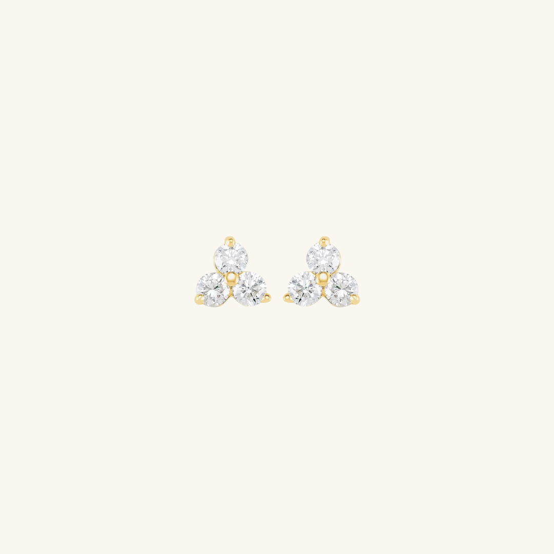 Pair of gold and diamond earrings on a light beige background
