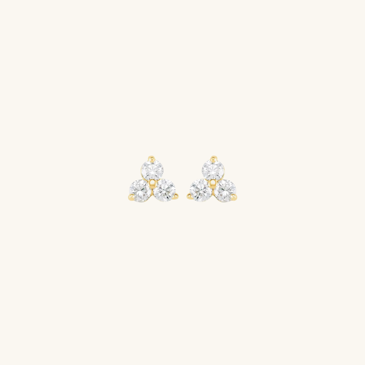 Pair of gold and diamond earrings on a light beige background