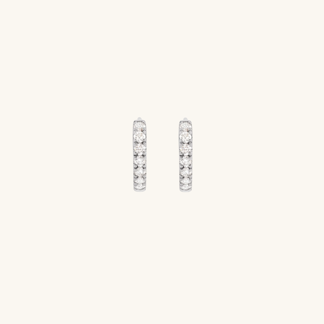 Pair of silver hoop earrings with clear stones on a light gray background